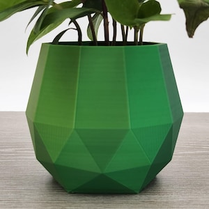 May include: A green geometric planter with a plant growing out of it.