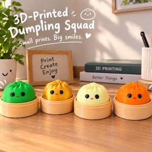 Könnte beinhalten: Vier 3D-gedruckte Knödel-Figuren in Grün, Gold, Hellgelb und Orange, die jeweils auf einem kleinen runden Sockel in Holzoptik stehen. Jeder Knödel hat zwei schwarze runde Augen und ein kleines rotes Lächeln. Text: 3D-Printed Dumpling Squad.