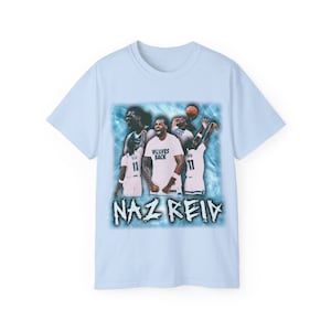 Puede incluir: Camiseta azul claro con un gráfico de estilo vintage de jugadores de baloncesto. El gráfico presenta a tres jugadores en acción, con el texto "Naz Reid" y "Wolves Back" impreso en la camiseta.