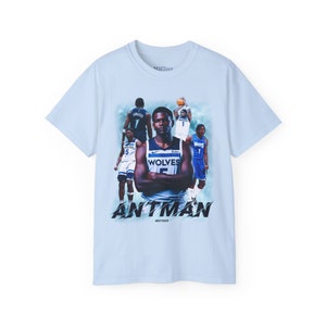 May include: Light blue t-shirt with a graphic print of a basketball player in a blue and white jersey with the text "WOLVES" and "ANTMAN" on the front.