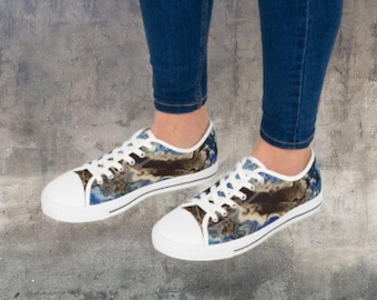 Può includere: Sneakers basse in tela bianca con stampa astratta blu e marrone. Le scarpe hanno lacci bianchi e un bordo nero intorno alla suola.