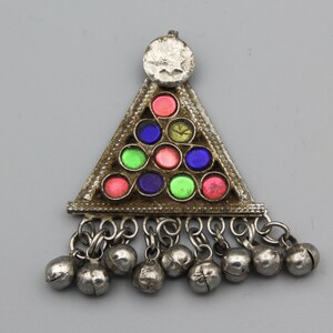 Puede incluir: Pendiente de plata con forma triangular y un diseño decorativo de cuentas de vidrio de colores. El pendiente tiene un pequeño disco redondo en la parte superior y una franja de cascabeles de plata.