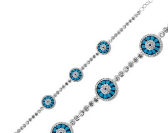 Pode incluir: Uma pulseira de prata com quatro pingentes circulares com um centro turquesa e um padrão de pedras brancas. A corrente da pulseira também é adornada com pequenas pedras brancas redondas. A pulseira é exibida em um fundo branco.
