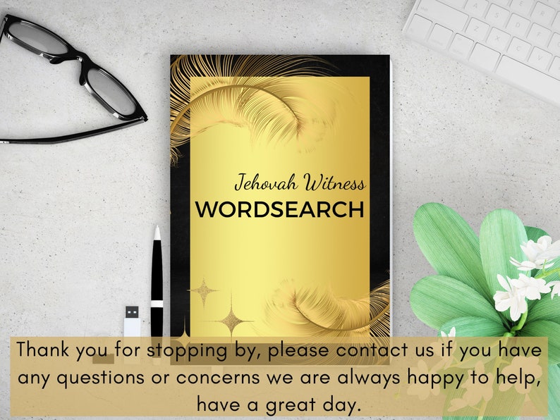 Puede incluir: Un libro negro y dorado con el t&iacute;tulo "Jehovah Witness WORDSEARCH" en la portada. La portada presenta un fondo dorado con plumas y estrellas doradas. El libro est&aacute; sobre una superficie blanca.