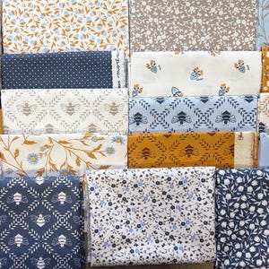 May include: A collection of folded fabric squares featuring various patterns including floral prints, small white daisies, repeating bee motifs, polka dots, and leafy vines in a color palette of navy blue, mustard yellow, light blue, white, and beige.
