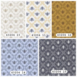 May include: A collection of five fabric swatches featuring a repeating diamond pattern formed by leafy vines with a bee centered in each diamond. The colorways include beige, blue and yellow, mustard, light blue, and dark gray, labeled 43204 23, 11, 12, 14, 15.