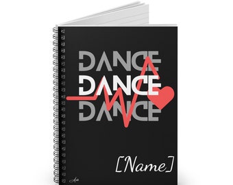 May include: Black spiral notebook with a white heart and a red heartbeat graphic. The text "DANCE" is repeated three times in white. The text "[Name]" is written in white at the bottom of the notebook.