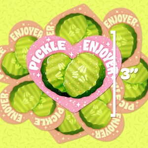 May include: A collection of heart-shaped stickers featuring pickle slices. The central sticker, measuring 7.6 cm, has a pink heart with the word "PICKLE" and "ENJOYER" around the edges. The stickers have a light green and pink color scheme.