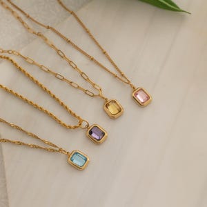 Puede incluir: Collares dorados con colgantes rectangulares de colores. Los colgantes presentan piedras preciosas azul claro, moradas, amarillas y rosas. Las cadenas tienen diferentes diseños. Joyería.