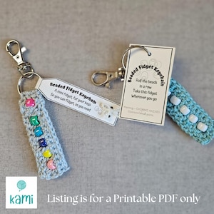 Könnte beinhalten: Zwei gehäkelte Perlen-Fidget-Schlüsselanhänger mit Anweisungen auf weißen Karten. Der Schlüsselanhänger links hat ein hellgraues gehäkeltes Band mit bunten Perlen. Der Schlüsselanhänger rechts hat ein hellblaues gehäkeltes Band mit weißen Perlen. Die Karten haben den Text "Beaded Fidget Keychain" und "Roll the beads in a row. Take this fidget wherever you go."