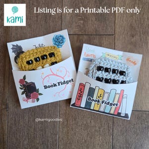 May include: Two crochet book fidgets in mustard yellow and light gray, each featuring black beads and white accents. They are displayed in white paper sleeves with printed illustrations of books, roses, and the text Book Fidget and Listing is for a Printable PDF only.