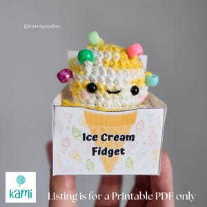 May include: A crocheted ice cream fidget toy with a smiling face, white and yellow yarn, and colorful bead sprinkles. The toy is in a small box that says "Ice Cream Fidget". The text "Listing is for a Printable PDF only" is at the bottom.