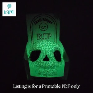May include: A glowing green skull fidget toy with a textured surface, set against a dark background. The toy is displayed in a tombstone-shaped package that reads "Skull Fidget" and "RIP". The text "Listing is for a Printable PDF only" is at the bottom.