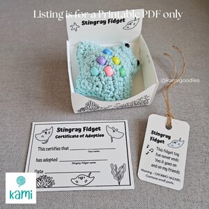 May include: A light blue crocheted stingray fidget toy with colorful bead accents, presented in a white box. Includes a certificate of adoption and a tag with text. The listing is for a printable PDF.