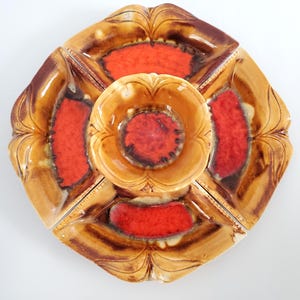May include: A ceramic serving dish with four sections and a central bowl. The dish is decorated with a brown and orange glaze.