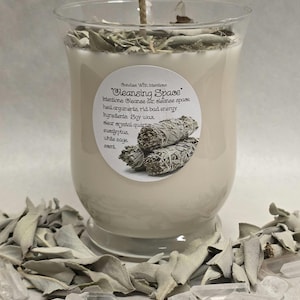 May include: A clear glass candle filled with off-white soy wax, topped with dried sage leaves and a central wick. The label reads: Candles With Intentions, Cleansing Space, Intentions: Cleanse air, cleanse space, heal arguments, rid bad energy. Ingredients: Soy wax, clear crystal quartz, eucalyptus, white sage, scent.