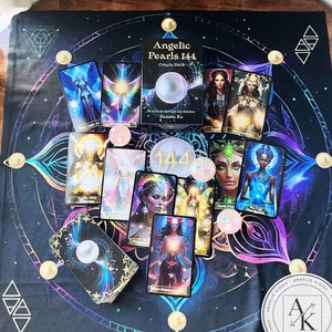 May include: An arrangement of oracle cards and crystals on a black and purple patterned cloth. The cards feature illustrations of angelic figures and the text "Angelic Pearls 144 Oracle Deck." The website address www.angelic-kisses.com is visible.