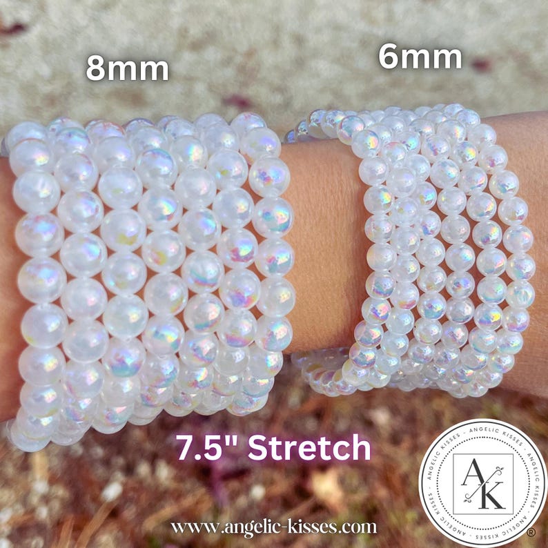 Op de afbeelding: Twee iriserende kralenarmbanden worden getoond, &eacute;&eacute;n met 8 mm kralen en de andere met 6 mm kralen. De armbanden zijn gemarkeerd als 7,5" stretch (ongeveer 19 cm). De armbanden zijn wit met een subtiele regenboogglans. De merknaam "Angelic Kisses" is zichtbaar.