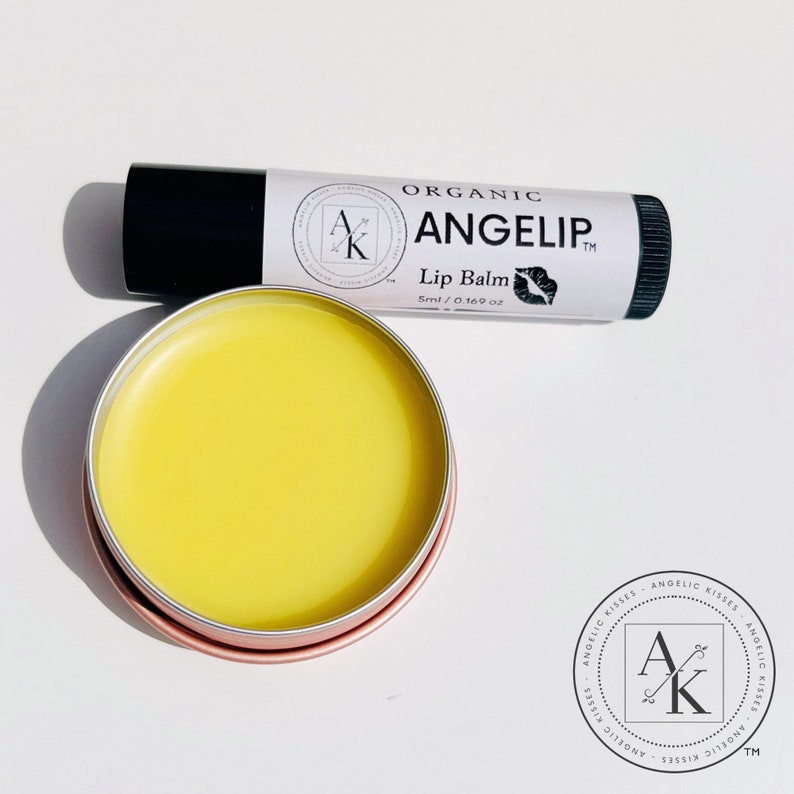 Peut inclure: Deux produits de baume &agrave; l&egrave;vres sont pr&eacute;sent&eacute;s. L'un est un tube avec un capuchon noir et une &eacute;tiquette blanche qui indique "ORGANIC ANGELIP Lip Balm 5ml / 0.169 oz". L'autre est une petite bo&icirc;te ronde remplie de baume jaune. Le r&eacute;cipient a un bord rose dor&eacute;.