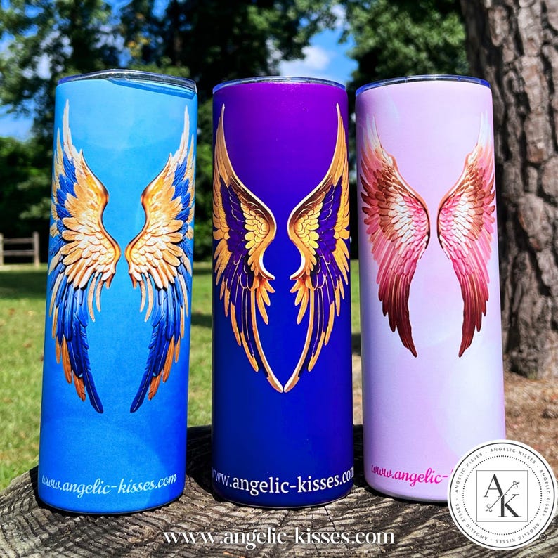 May include: Three stainless steel tumblers with angel wing designs. The tumblers are blue, purple, and pink, each featuring a different color scheme for the wings. The blue tumbler has gold and blue wings, the purple has gold wings, and the pink has pink wings. The website address is printed on each tumbler.