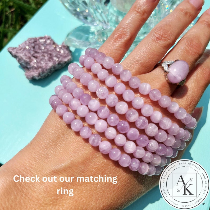 May include: A stack of light purple beaded bracelets and a matching ring with a large, oval-shaped stone. The bracelets are made of small, round beads. The ring is silver-toned. The image also includes a piece of raw, light purple stone and the text "Check out our matching ring."