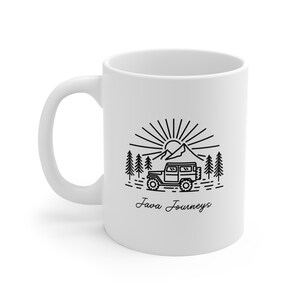 May include: White ceramic coffee mug with a black line drawing of a mountain scene, a sun, trees, and a jeep. The text "Java Journeys" is below the image.
