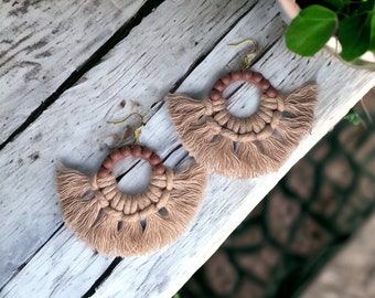 May include: A pair of beige and brown macrame earrings with a circular design and fringe details.