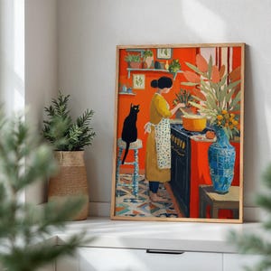 K&ouml;nnte beinhalten: Ein gerahmter Kunstdruck zeigt eine K&uuml;chenszene mit einer kochenden Person. Das Kunstwerk zeigt eine schwarze Katze, eine blaue Vase und einen leuchtend orangefarbenen Hintergrund. Die Person tr&auml;gt ein gelbes Kleid und eine Sch&uuml;rze.