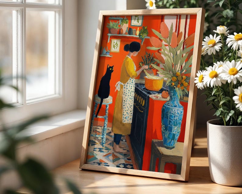K&ouml;nnte beinhalten: Gerahmter Kunstdruck, der eine Frau in einem gelben Kleid und einer Sch&uuml;rze beim Kochen in einer K&uuml;che zeigt. Eine schwarze Katze sitzt auf einem Hocker. Das Kunstwerk hat einen leuchtend orangefarbenen Hintergrund, eine blaue Vase und einen Blumenstrau&szlig;.