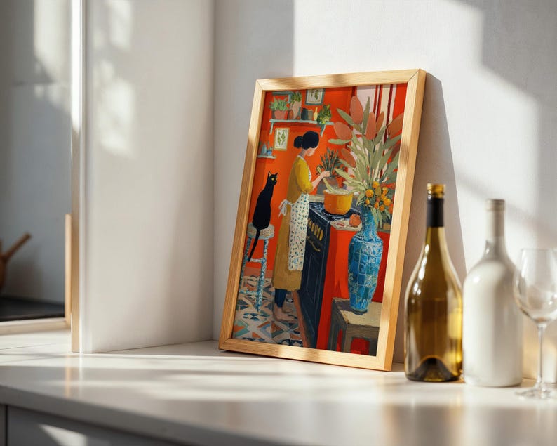K&ouml;nnte beinhalten: Ein gerahmter Kunstdruck zeigt eine K&uuml;chenszene mit einer kochenden Frau, einer schwarzen Katze und einem leuchtend orangefarbenen Hintergrund. Das Kunstwerk zeigt ein gelbes Kleid, eine blaue Vase und einen Holzrahmen, was eine warme Atmosph&auml;re schafft.