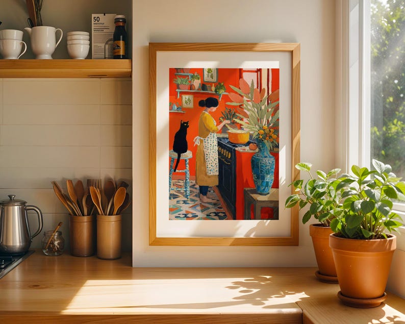 K&ouml;nnte beinhalten: Ein gerahmter Kunstdruck zeigt eine Person, die in einer K&uuml;che mit einer schwarzen Katze kocht. Das Kunstwerk zeigt eine leuchtend rote Wand, einen schwarzen Herd und eine blaue Vase. Die Person tr&auml;gt ein gelbes Kleid und eine wei&szlig;e Sch&uuml;rze.