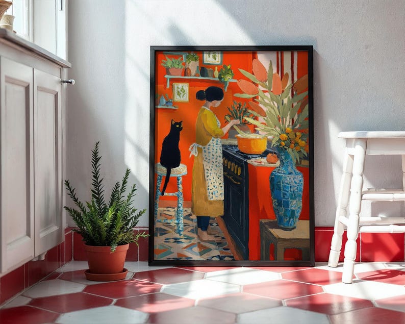 K&ouml;nnte beinhalten: Ein gerahmter Kunstdruck, der eine K&uuml;chenszene mit einer kochenden Person zeigt. Das Kunstwerk zeigt eine schwarze Katze, eine blaue Vase und ein lebendiges Farbenschema aus Orange und Rot. Eine Topfpflanze und ein wei&szlig;er Hocker befinden sich im Vordergrund.