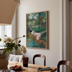 May include: A framed art print depicts a person relaxing in a hammock in a lush forest. The artwork features a person in white clothing, black shoes, and a black hat. The print is in a wooden frame and hangs on a white wall.