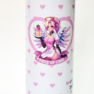 Puede incluir: Un vaso de acero inoxidable blanco con un patr&oacute;n de corazones rosas y un dise&ntilde;o en forma de coraz&oacute;n rosa con un &aacute;ngel de dibujos animados sosteniendo un pedazo de pastel. El texto "PIECE OF CAKE" est&aacute; impreso debajo del dise&ntilde;o.