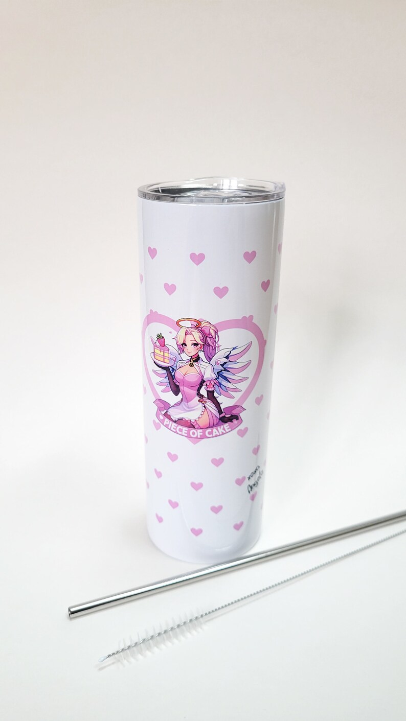Puede incluir: Un vaso de acero inoxidable blanco con un patr&oacute;n de corazones rosas y una ilustraci&oacute;n rosa y blanca de una mujer con alas de &aacute;ngel sosteniendo un pedazo de pastel. El texto "Piece of Cake" est&aacute; impreso debajo de la ilustraci&oacute;n. El vaso viene con una pajita de acero inoxidable y un cepillo de limpieza.