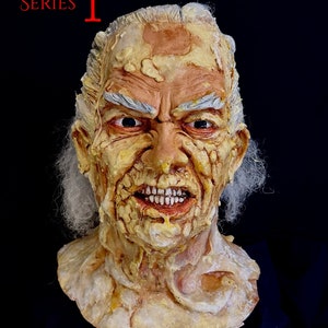 Puede incluir: Primer plano de una máscara detallada, realista, grotesca e inquietante de un anciano con el rostro arrugado, cabello blanco y una expresión amenazante. La máscara está hecha de un material que parece piel y tiene mucha textura. La máscara es un accesorio para una película de terror o un disfraz de Halloween.