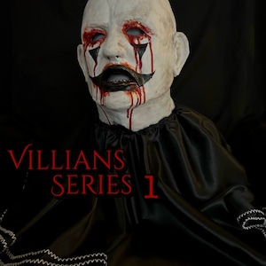 Pode incluir: Uma máscara branca com olhos pintados de preto e uma boca pintada de preto. A máscara está coberta de tinta vermelha que parece sangue. A máscara está sentada em um fundo de tecido preto com o texto "VILLIANS SERIES 1" em vermelho.