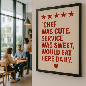Op de afbeelding: Een ingelijste poster met een zwarte rand hangt aan een witte muur. De poster heeft een crèmekleurige achtergrond met rode tekst die luidt: "Chef was schattig, service was lief, zou hier dagelijks eten." Vijf rode sterren en een hart staan boven en onder de tekst.