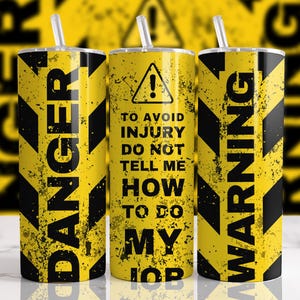 May include: Three yellow and black tumblers with straws. The tumblers have a distressed design with the words "DANGER" and "WARNING" in large black letters. The center tumbler has a warning symbol and the text "TO AVOID INJURY DO NOT TELL ME HOW TO DO MY JOB."