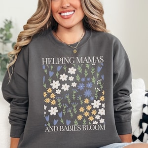 May include: Grey sweatshirt with a floral design and the text "Helping Mamas and Babies Bloom".