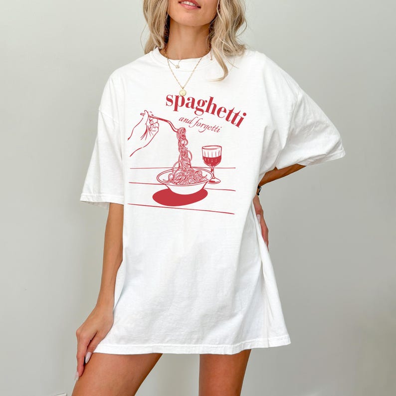 May include: White oversized t-shirt with a red graphic of a plate of spaghetti and a glass of wine. The text on the shirt reads "spaghetti and forgetti."