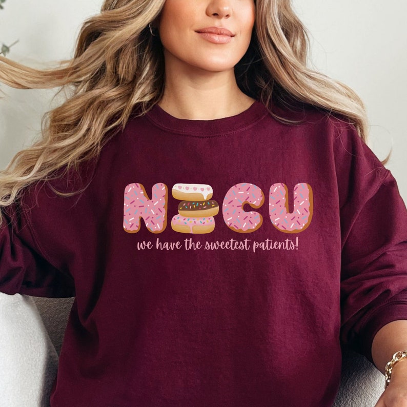 Pode incluir: Camisola de cor bord&ocirc; com um gr&aacute;fico da palavra "NICU" escrita com donuts. O texto abaixo dos donuts diz "we have the sweetest patients!"