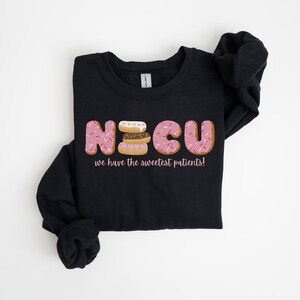 Pode incluir: Camisola de moletom preta com um gr&aacute;fico de donuts que soletram "NICU" e o texto "we have the sweetest patients!"
