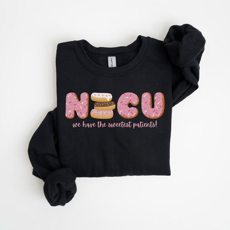 Pode incluir: Camisola de moletom preta com um gr&aacute;fico de donuts que soletram "NICU" e o texto "we have the sweetest patients!"