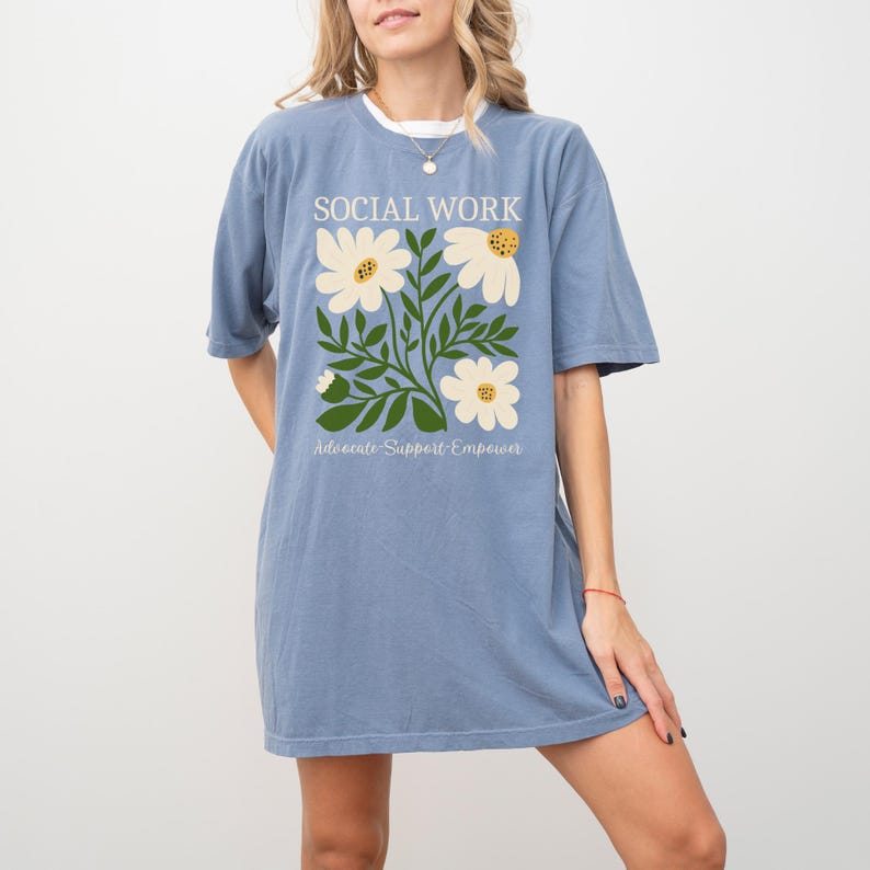 May include: A light blue t-shirt with a floral design and the text "Social Work Advocate Support Empower".