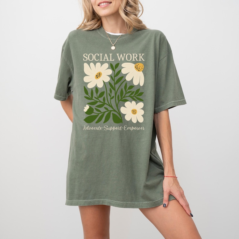 May include: A green t-shirt with a floral design and the text "Social Work Advocate-Support-Empower".