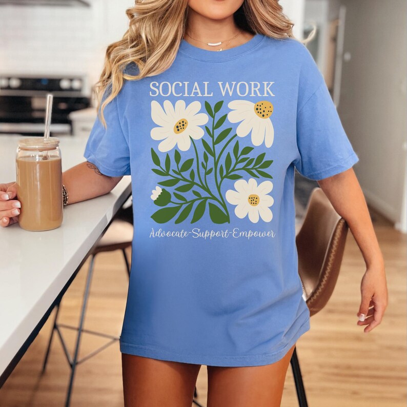 May include: A light blue t-shirt with a floral design and the text "SOCIAL WORK Advocate-Support-Empower".