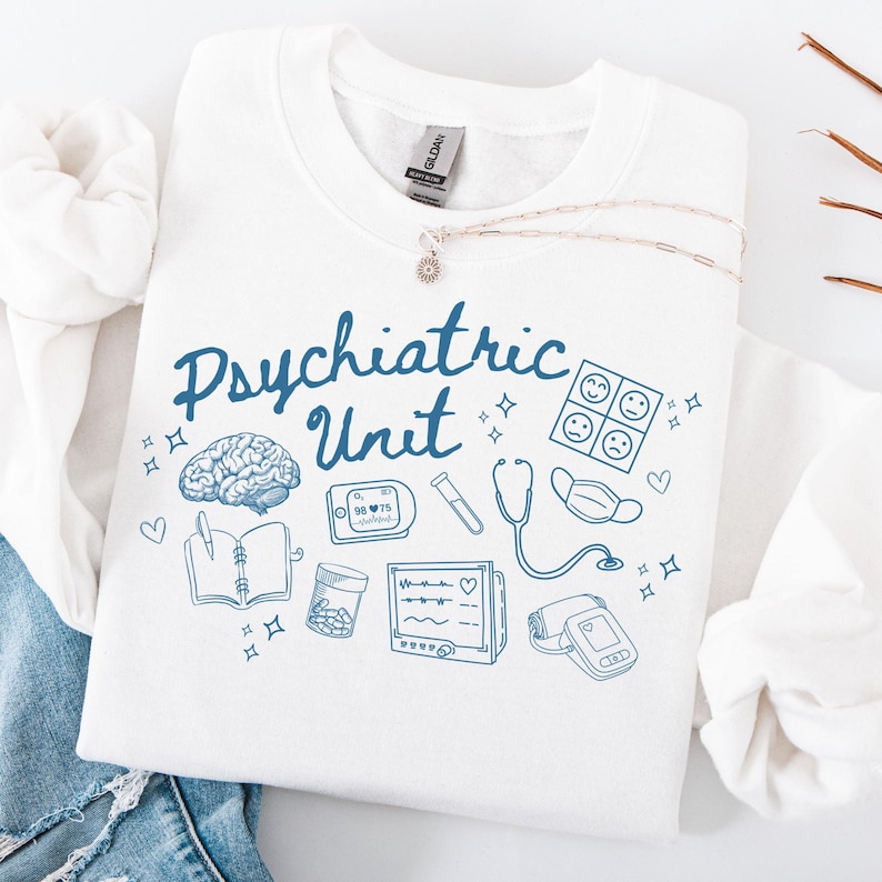 May include: White sweatshirt with blue text that reads "Psychiatric Unit" and blue illustrations of medical equipment, including a brain, a stethoscope, a notebook, a pill bottle, a blood pressure cuff, and a heart monitor.