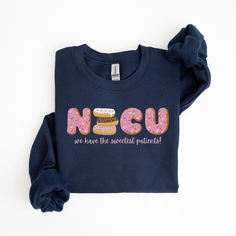 Pode incluir: Uma camisa de moletom azul marinho com um gr&aacute;fico de donuts que soletram "NICU" e o texto "we have the sweetest patients!"