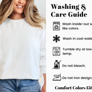 Op de afbeelding: Een witte Comfort Colors 1566 sweatshirt. De afbeelding bevat een was- en verzorgingsgids met instructies: binnenstebuiten wassen met dezelfde kleuren, wassen in koud water, in de droger op lage temperatuur, niet bleken en het ontwerp niet strijken.